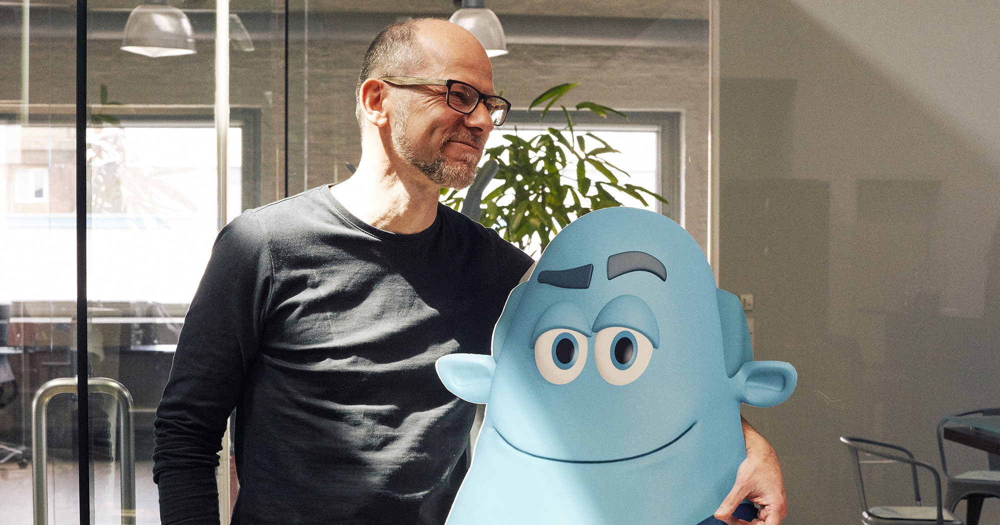 Man sieht einen FederhenSchneider Mitarbeiter, der eine blaue Pappfigur mit Blaumann umarmt.