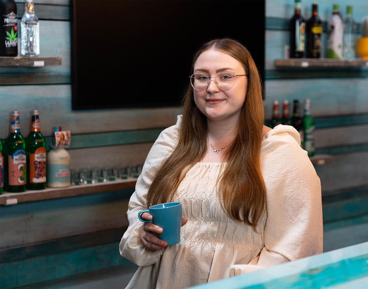Unsere Auszubildende Eileen steht an unserer Surferbar und hält einen Kaffee in der Hand.