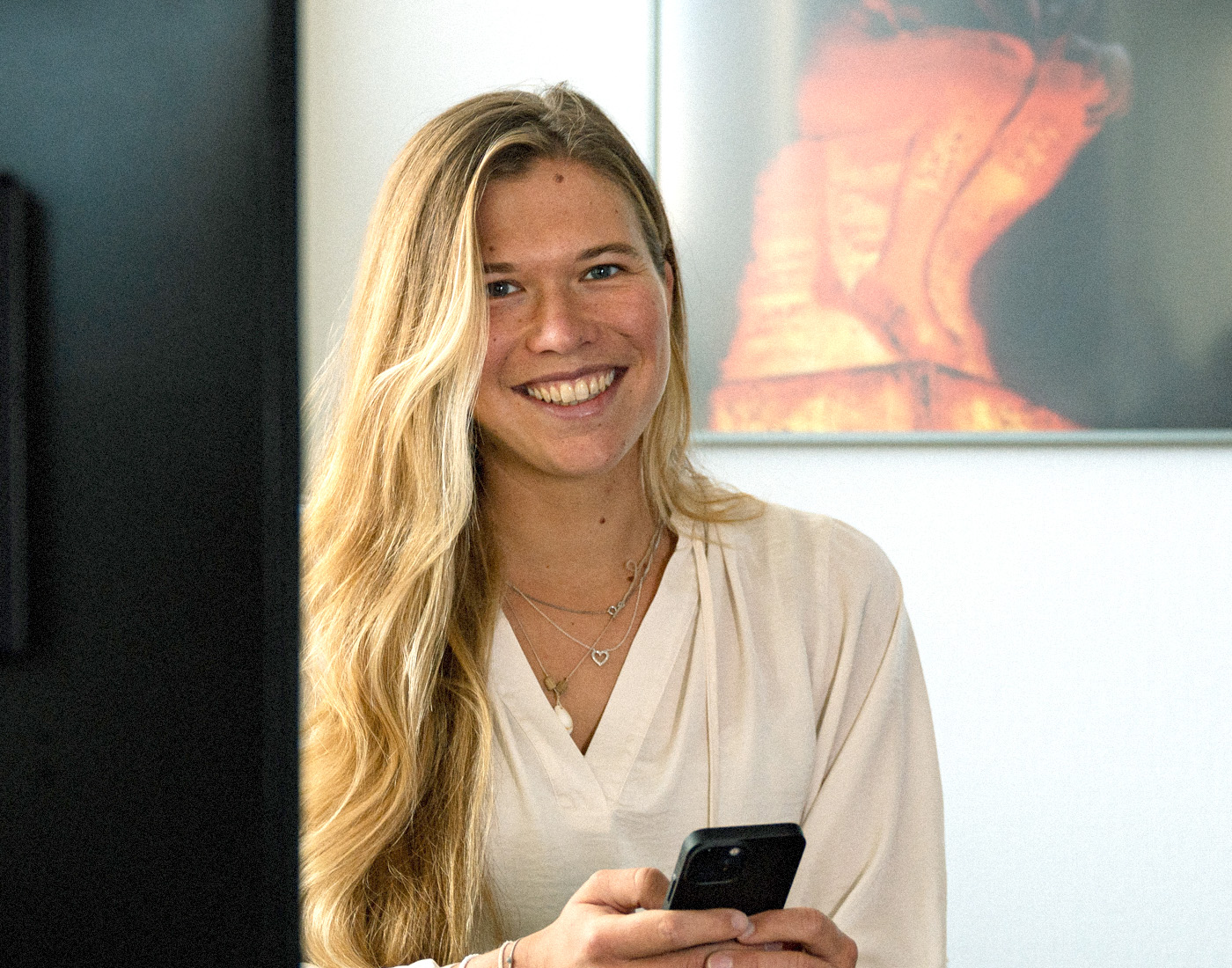 Unser Teamlead Social Media Linda sitzt mit ihrem Handy in der Hand hinter ihrem Laptop.