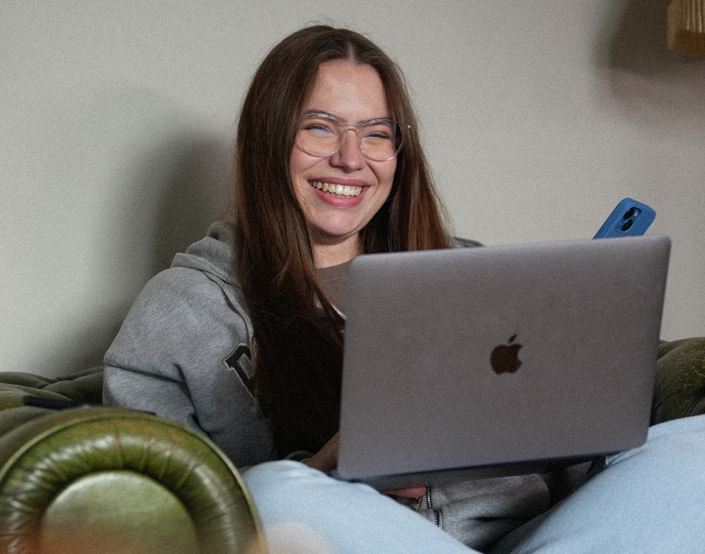 Unsere duale Studentin Social Media Merle hat den Laptop auf dem Schoß und das Handy in der Hand.