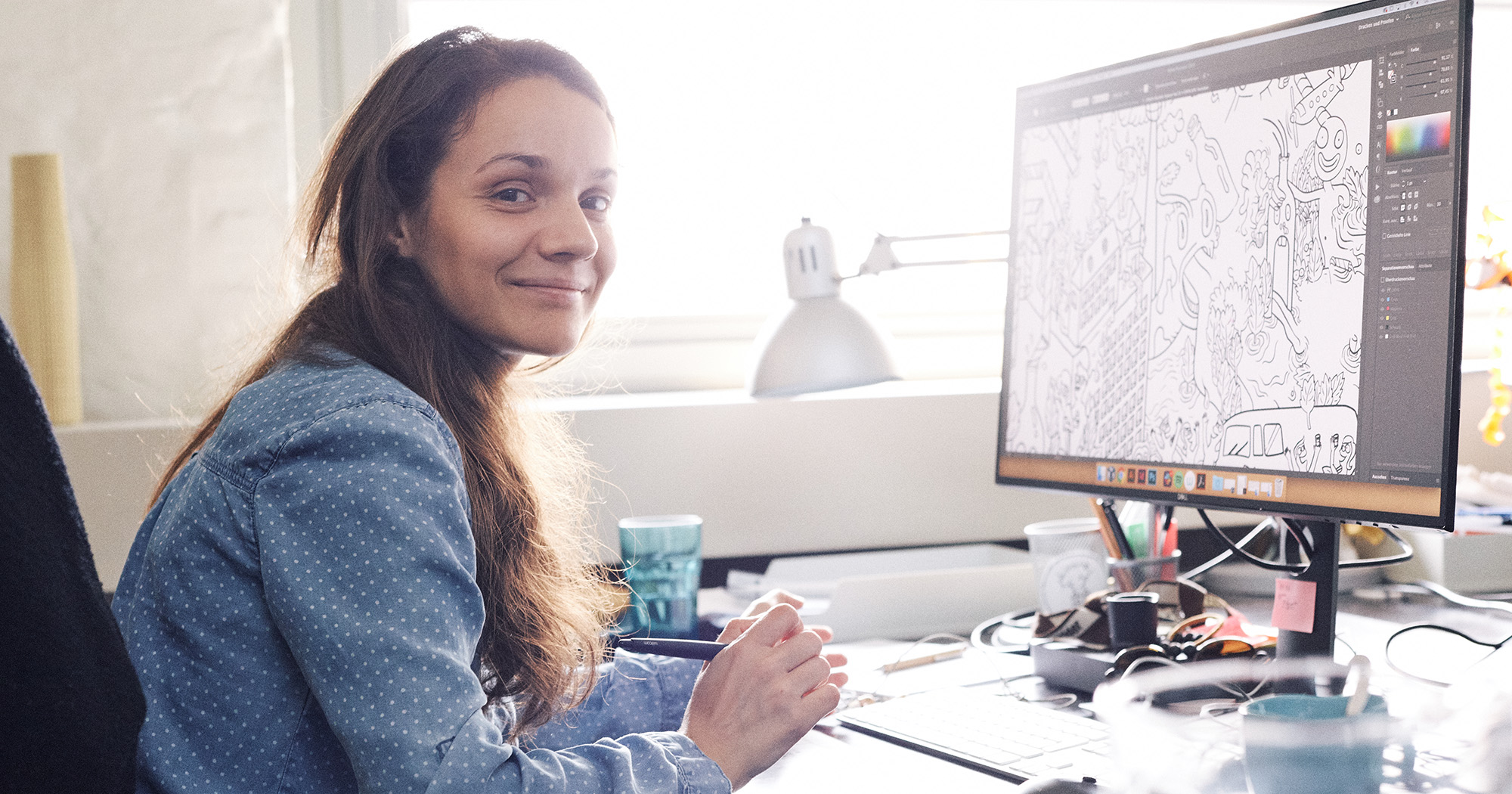 Dieses Bild zeigt eine FederhenSchneider Mitarbeiterin am Schreibtisch, die seitlich in die Kamera schaut. Auf ihrem Monitor ist eine Comic-Illustration zu sehen. 