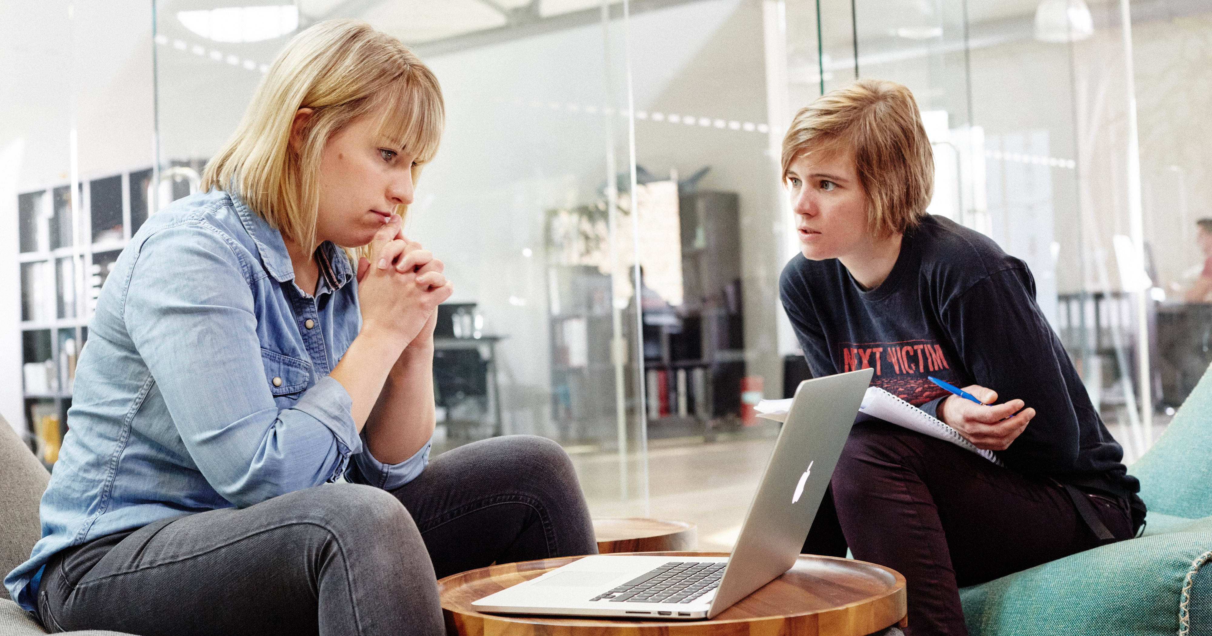 Dieses Bild zeigt zwei FederhenSchneider Mitarbeiterinnen, die auf Sitzsäcken sitzen, vor sich ein Laptop. Sie sehen nachdenklich aus. 