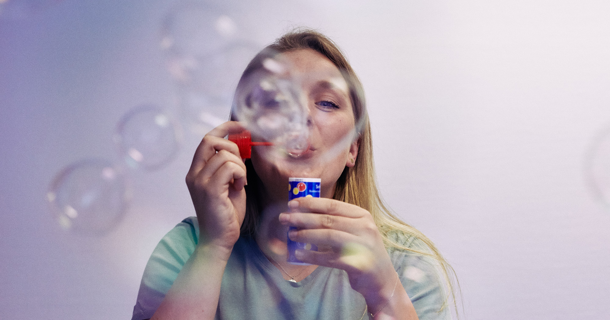 Dieses Bild zeigt eine FederhenSchneider Mitarbeiterin, die Seifenblasen in die Kamera pustet.