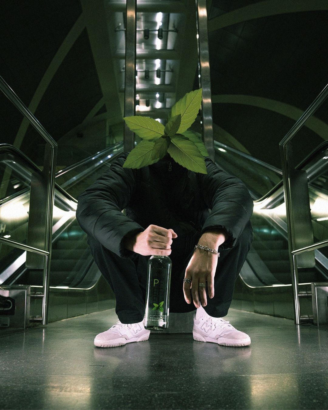 Junger Mann mit PFEFFI Flasche vor einer Rolltreppe