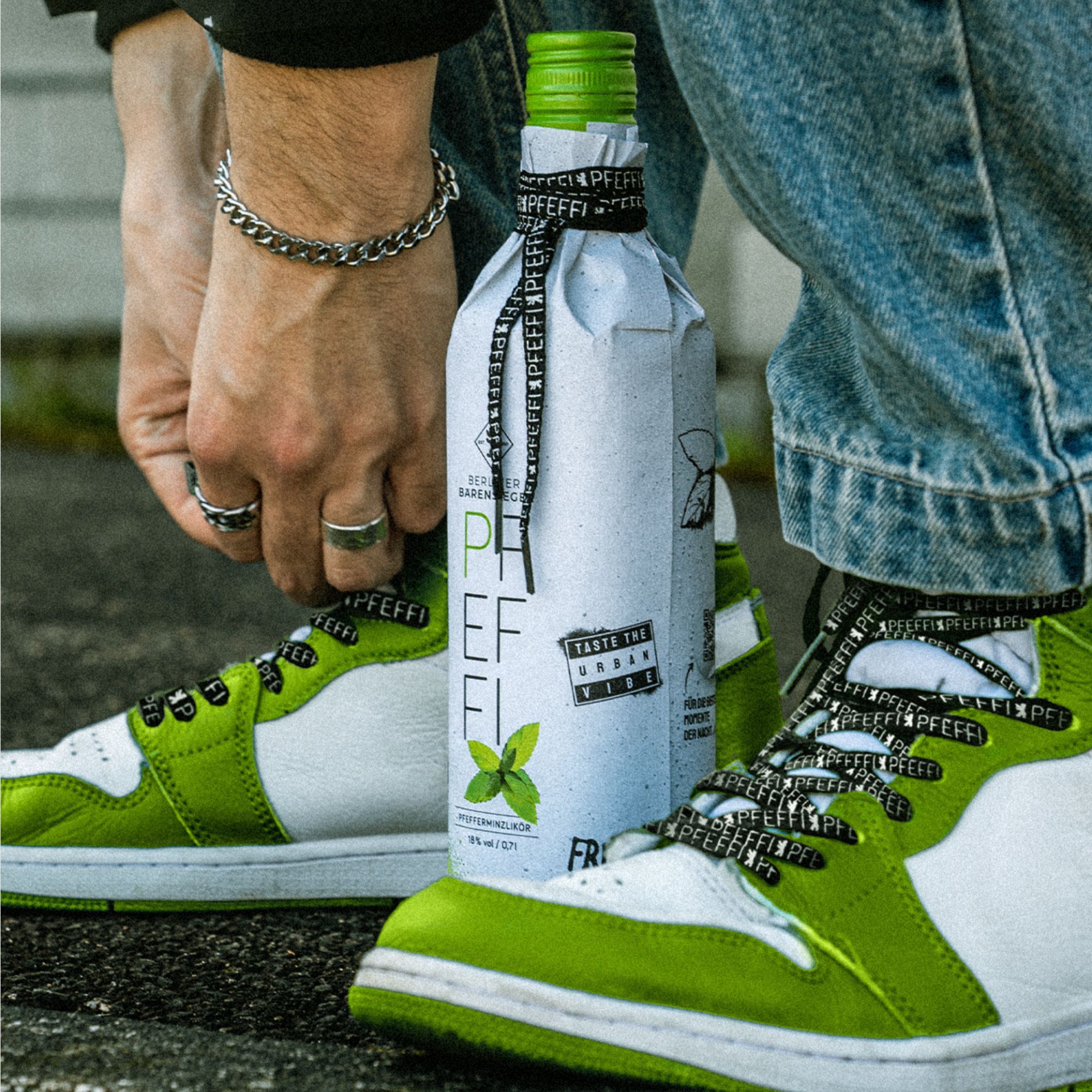 PFEFFI Flasche zwischen Sneakern mit PFEFFI Schnürsenkeln