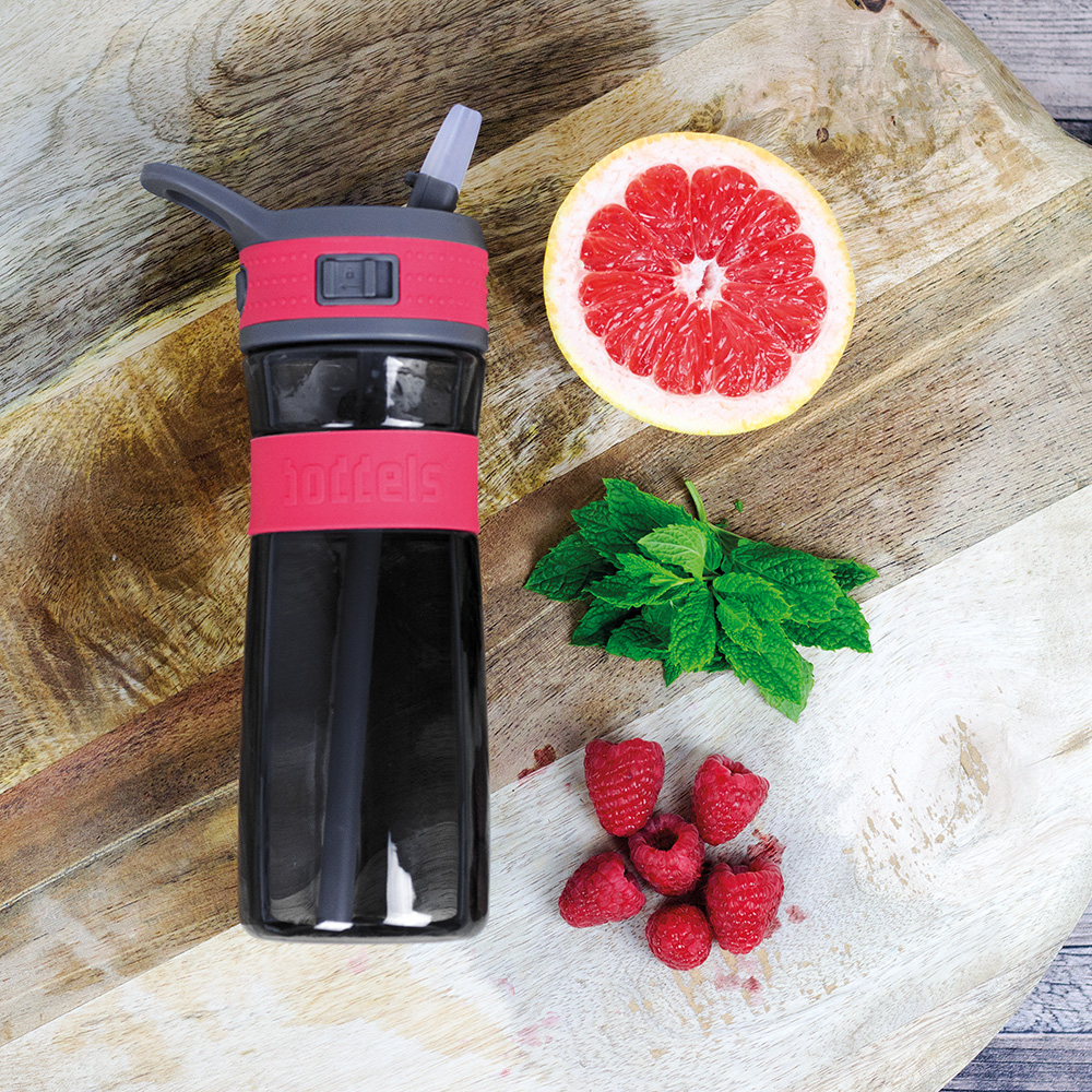 Das Foto zeigt eine Boddels Trinkflasche in pink nebst Grapefruit, Minzblättern und Himbeeren auf einem Schneidebrett aus Holz liegend.