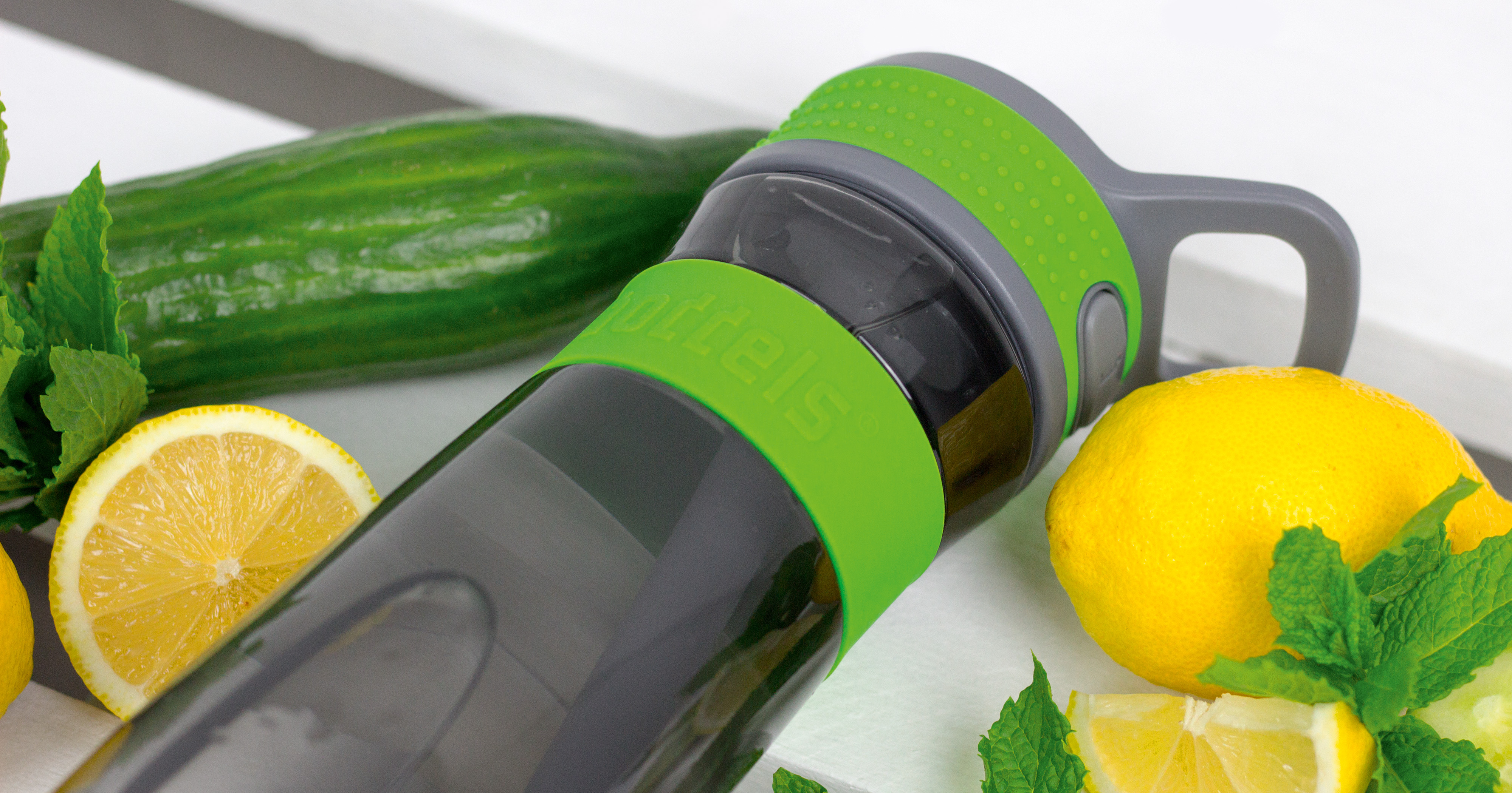 Das Foto zeigt eine Boddels Trinkflasche in grün nebst Gurke, Minze und Zitrone liegend.