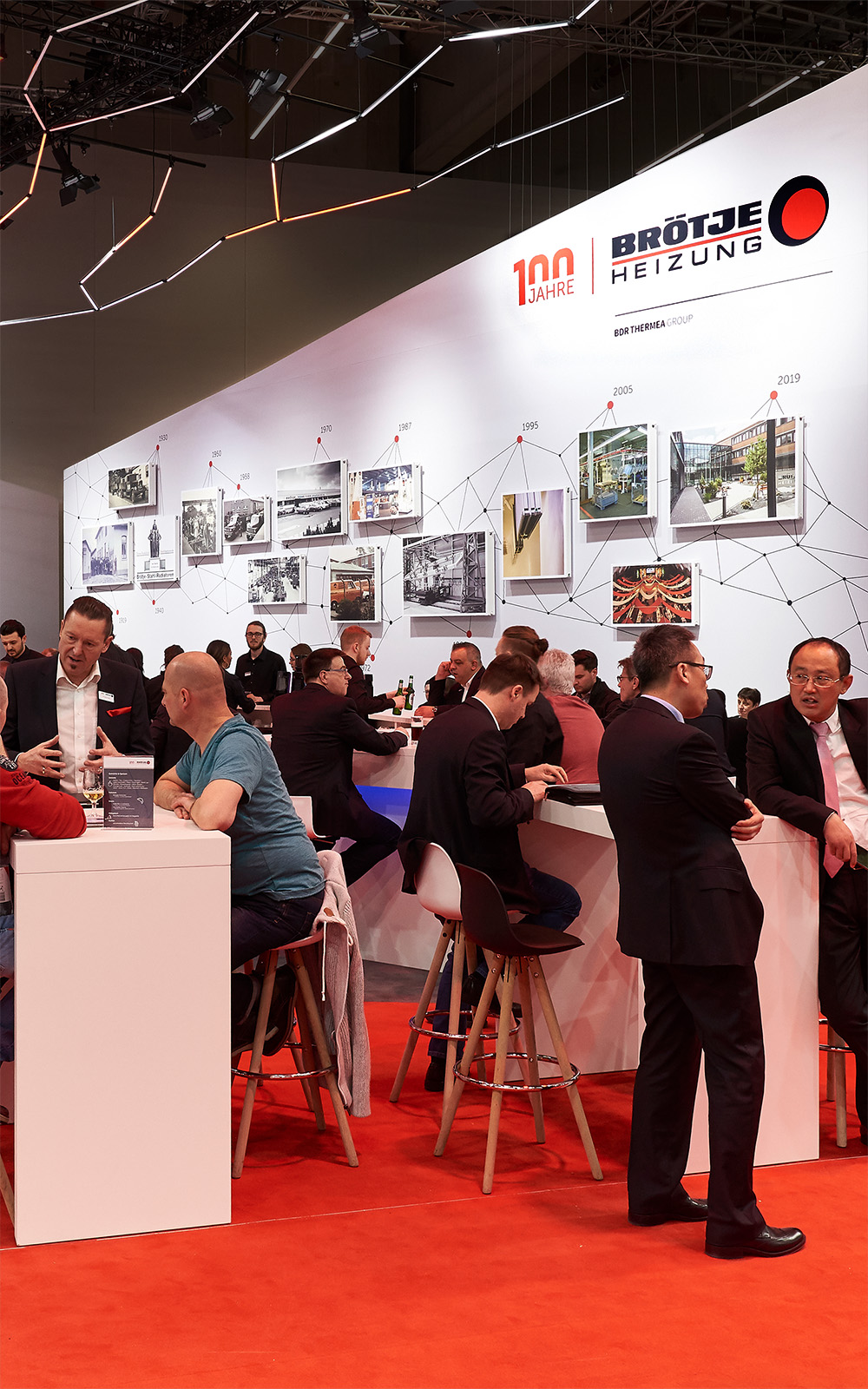 Das Foto zeigt den Catering-Bereich des Messestands von BRÖTJE mit Blick auf den Messeclaim „Neue Energie erleben“. Der Stand ist sehr belebt, Menschen unterhalten sich oder erkunden die Ausstellungsstücke.