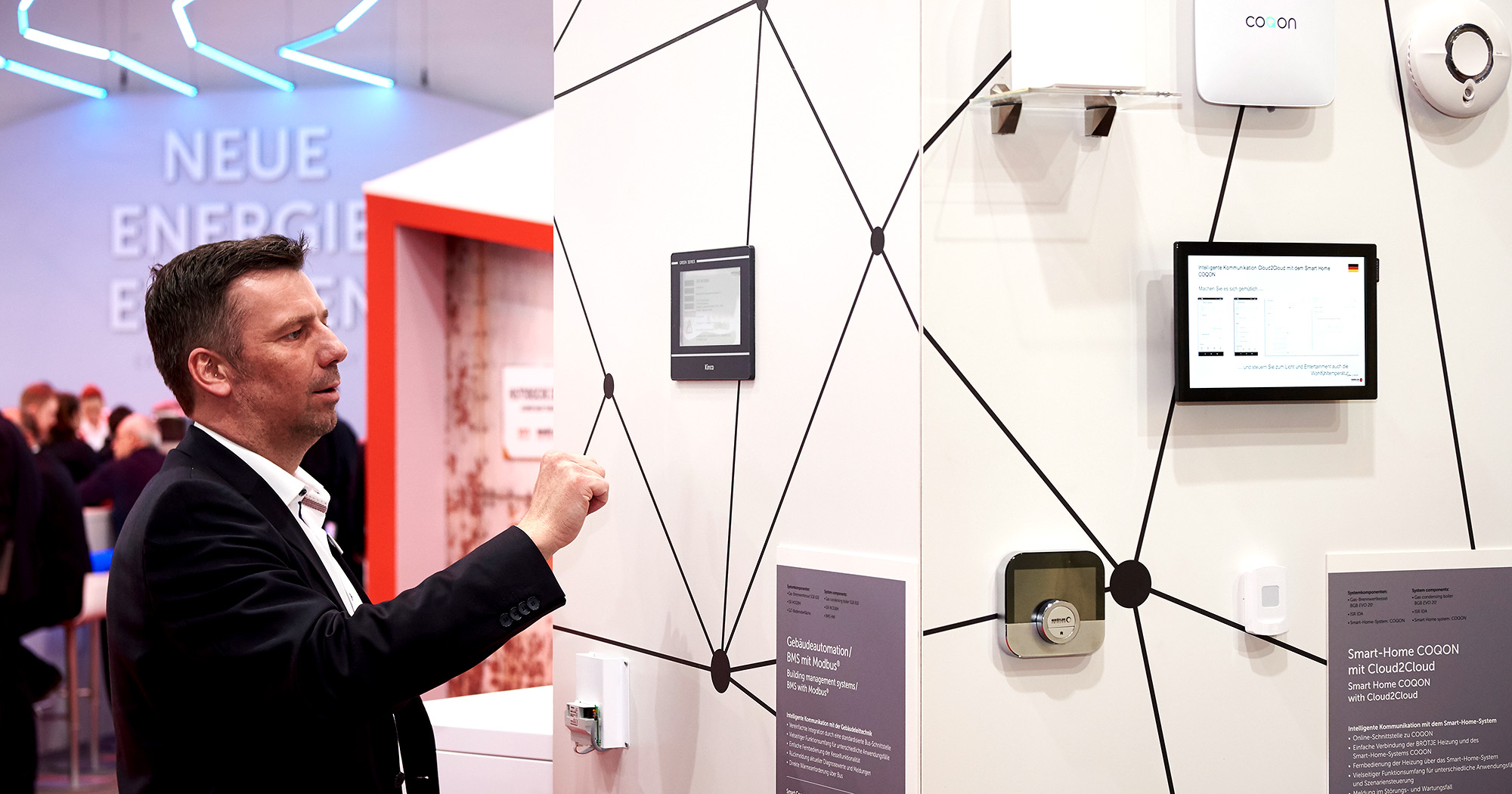 Das Foto zeigt einen Messebesucher, der vor einem Touchscreen auf dem BRÖTJE Messestand steht. Daneben ein Schild mit der Aufschrift: „Gebäudeautomation/BMS mit Modbus“.