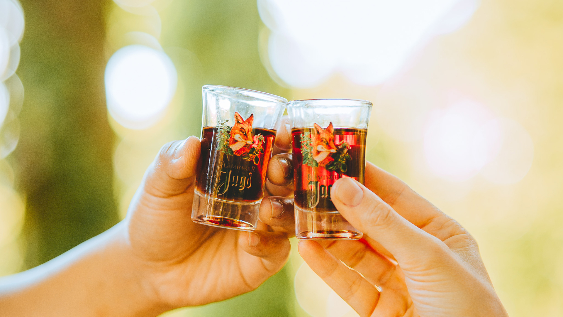 Zwei Personen stossen mit gebrandeten Pinnchen an