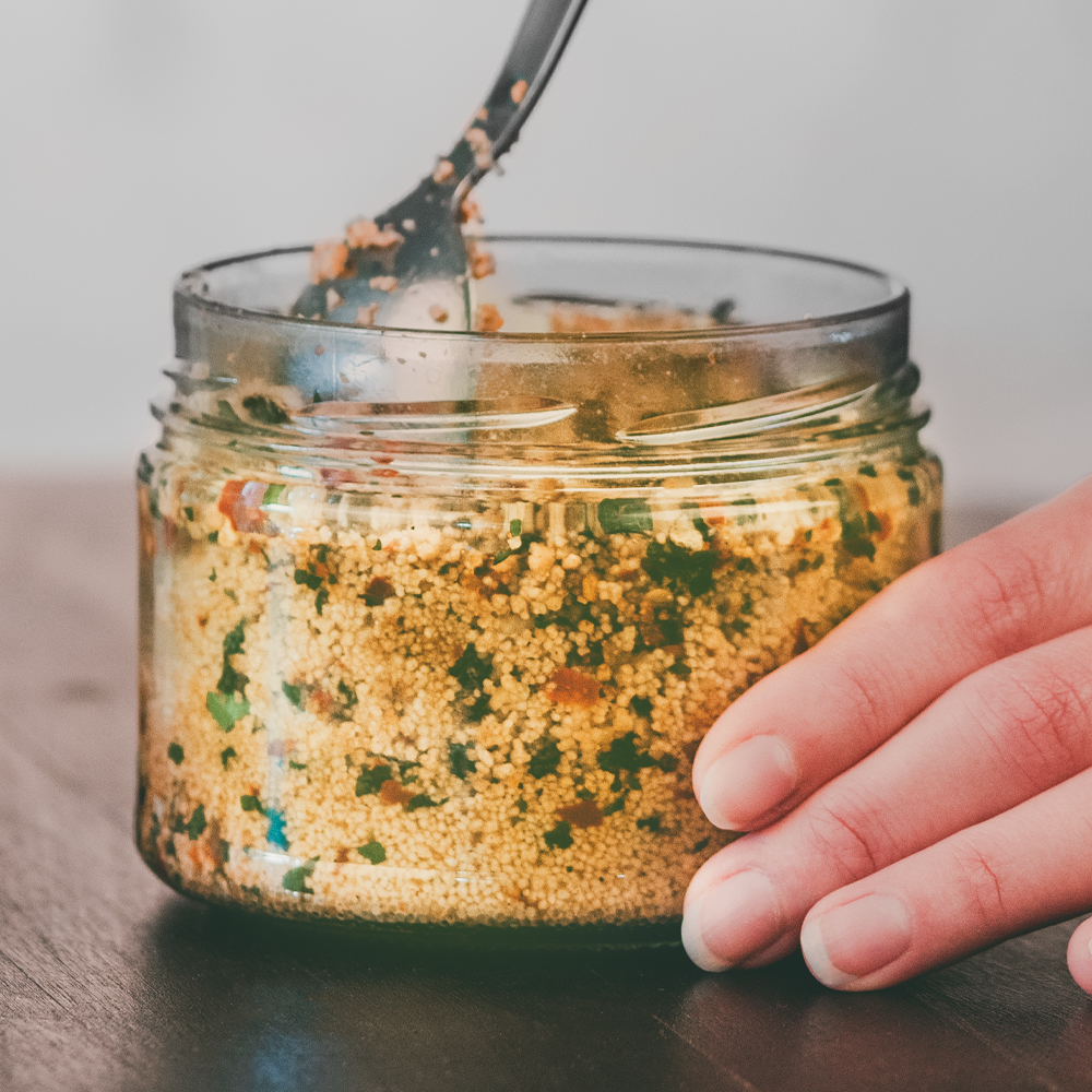 Ein geöffnetes und ein ungeöffnetes Glas Couscous auf einer Tischfläche