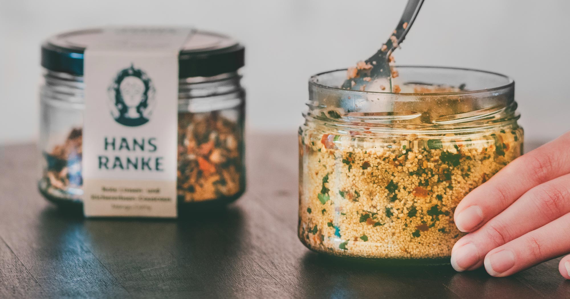 Ein geöffnetes und ein ungeöffnetes Glas Couscous auf einer Tischfläche