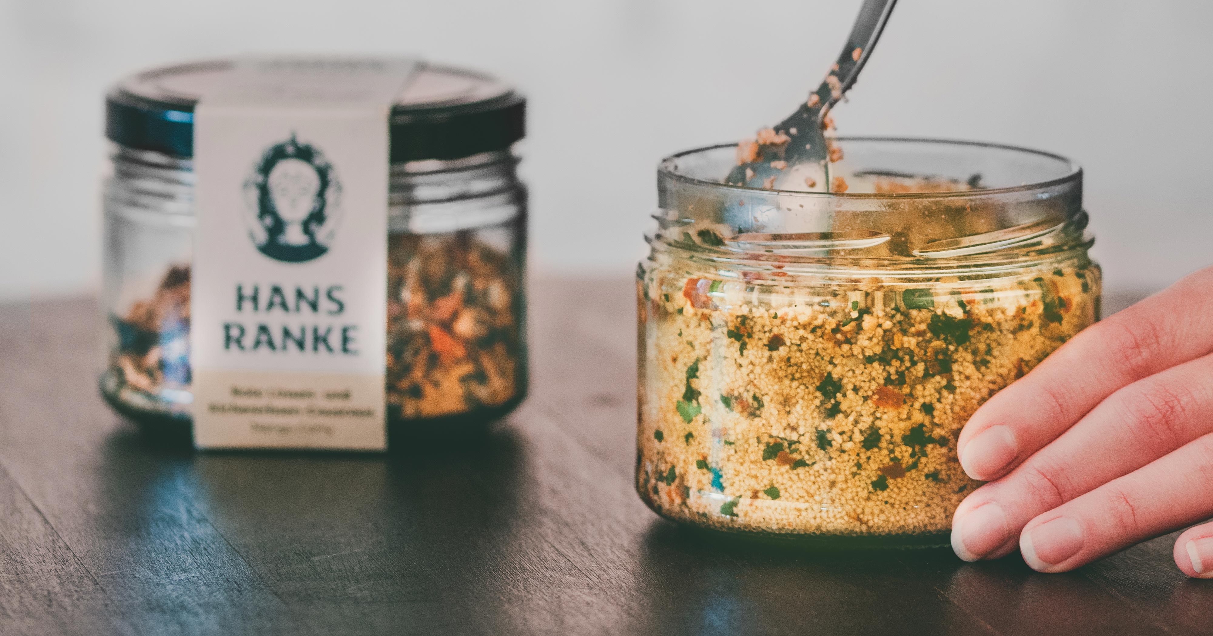 Ein geöffnetes und ein ungeöffnetes Glas Couscous auf einer Tischfläche