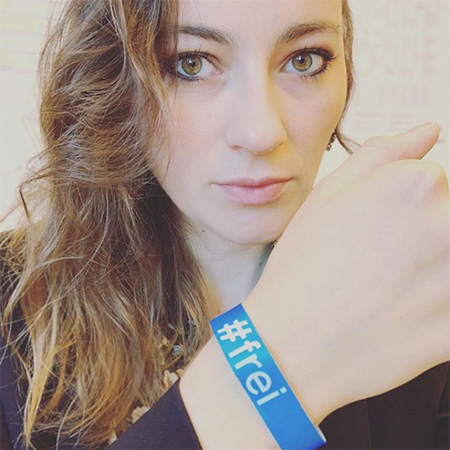 Das Foto zeigt den Oberkörper einer dunkelhaarigen Frau, die ihren Arm mit blauem #frei Band in die Kamera hält.