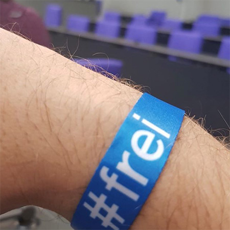 Das Foto zeigt einen Arm mit blauem #frei Band, der ins Bild ragt.