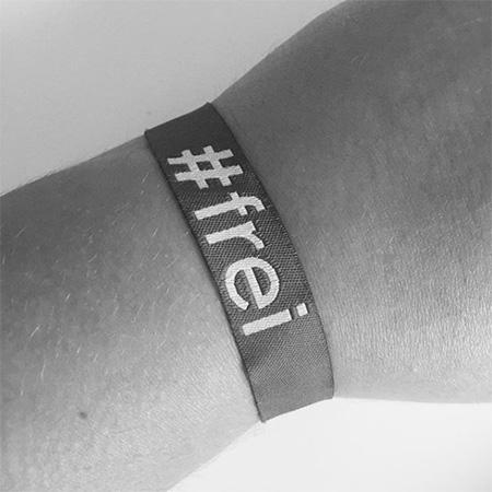 Das Foto zeigt ein #frei Band mit Arm aus nächster Nähe in schwarz/weiß.