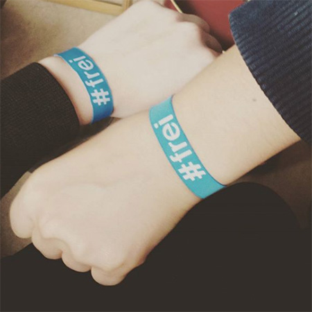 Das Foto zeigt zwei ausgestreckte Arme mit #frei Bändern, die von links und rechts ins Bild gehalten werden.