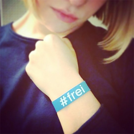 Das Foto zeigt eine Frau, die ihren Arm mitsamt #frei Band am Handgelenk in die Kamera hält.