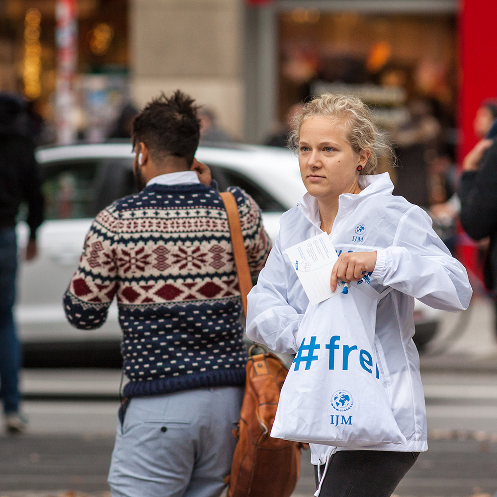 Das Bild zeigt eine Frau auf der Straße mit einer Tüte in der Hand auf der „#frei“ steht.