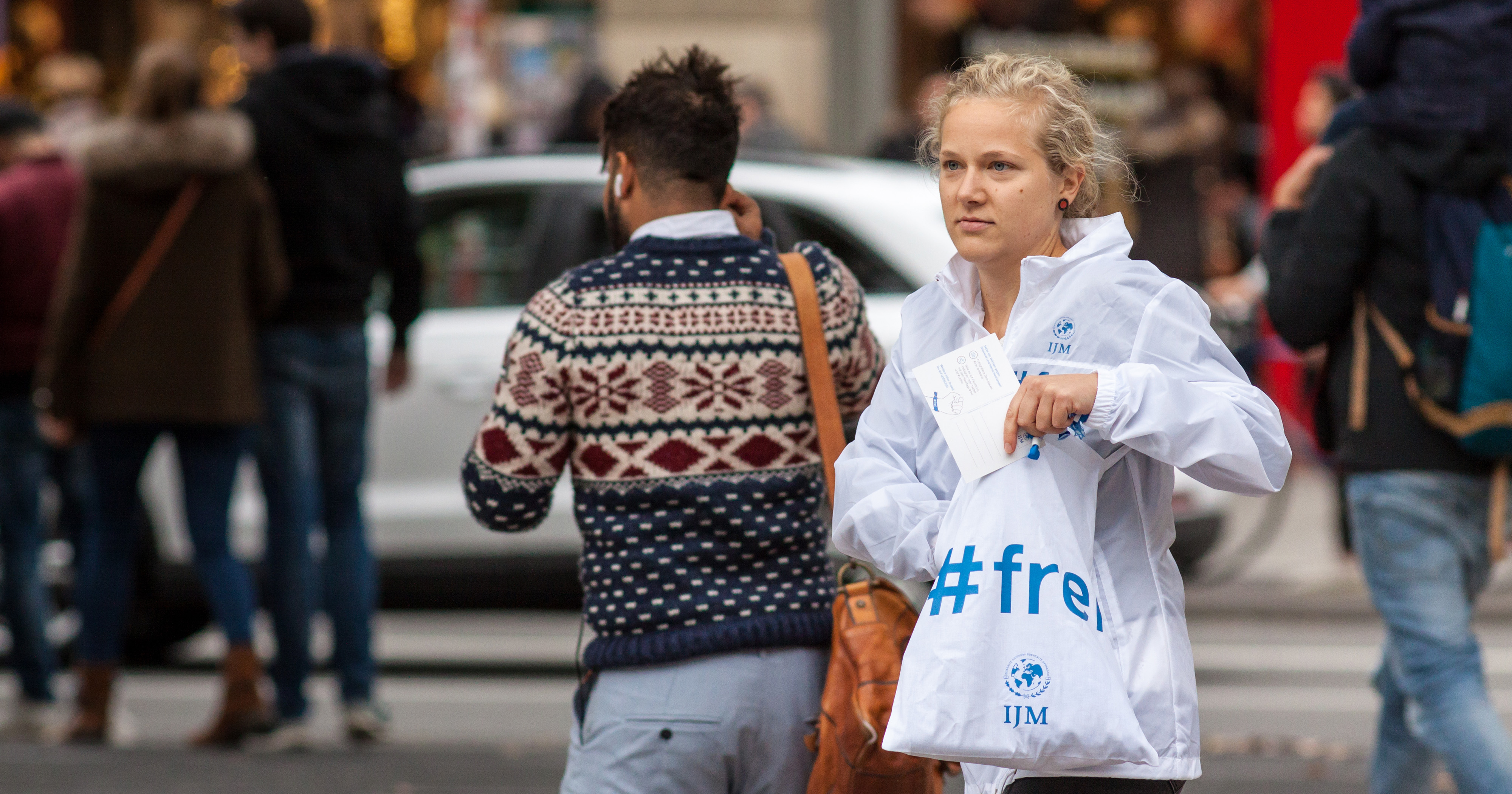 Das Bild zeigt eine Frau auf der Straße mit einer Tüte in der Hand auf der „#frei“ steht.