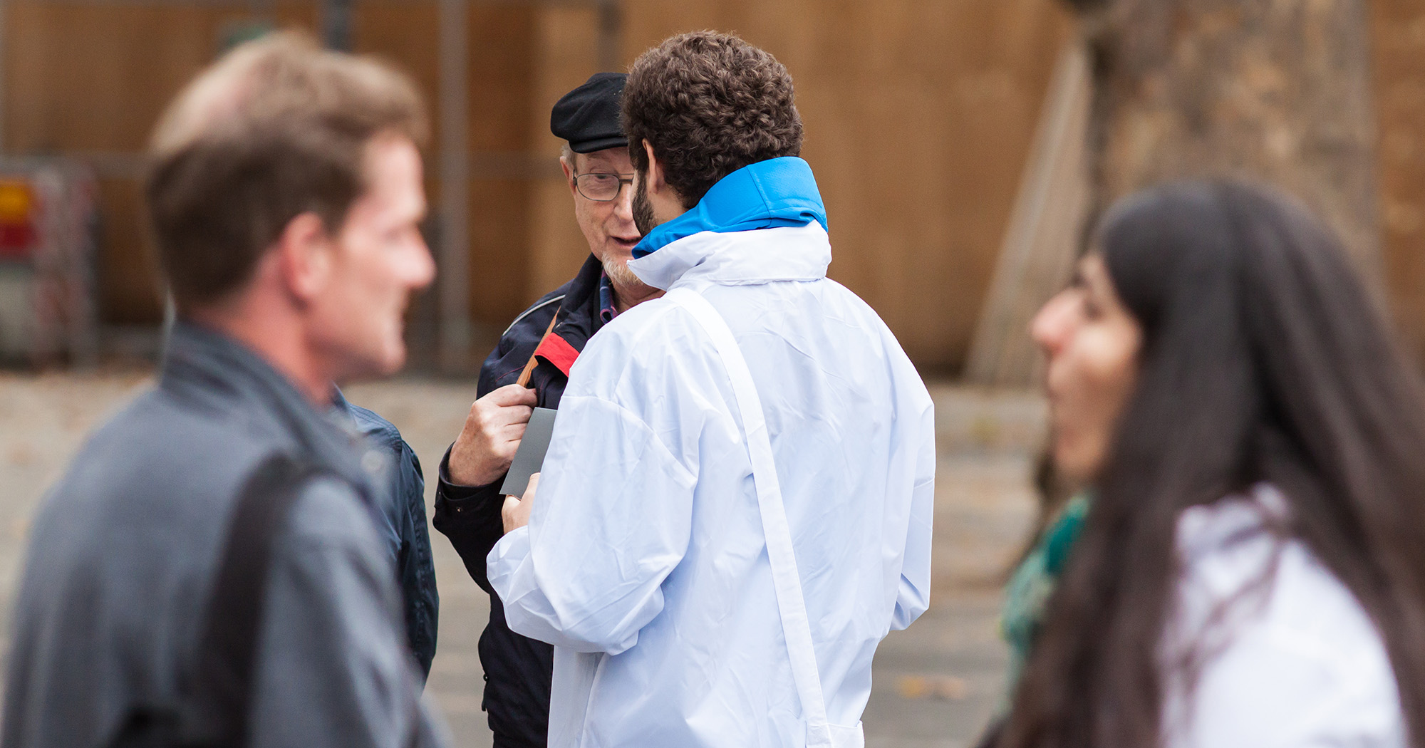 Das Bild zeigt einen Mann auf der Straße von hinten. Er redet mit einem anderen Mann.