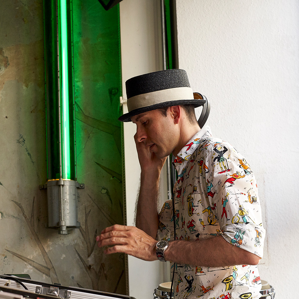 Das Foto zeigt einen DJ vor einer grünen Neonröhre.