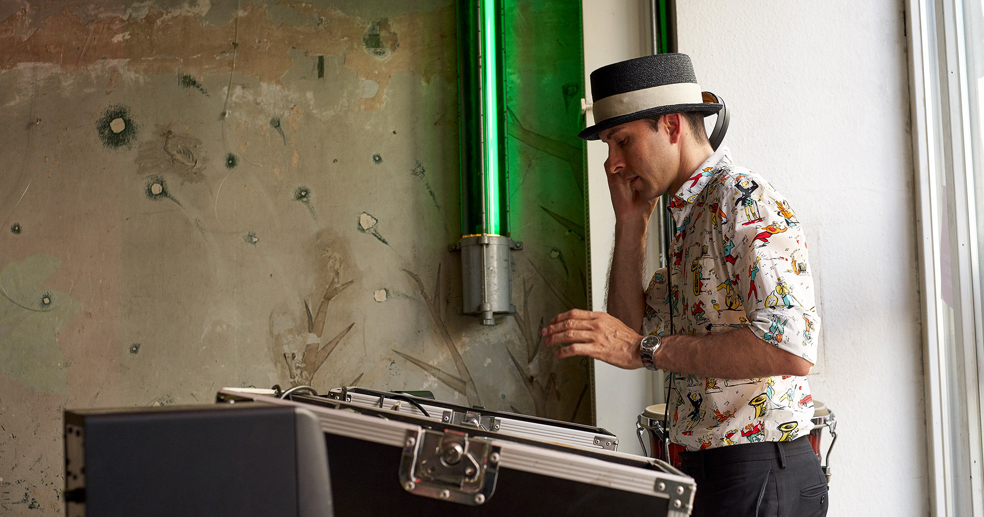 Das Foto zeigt einen DJ vor einer grünen Neonröhre.