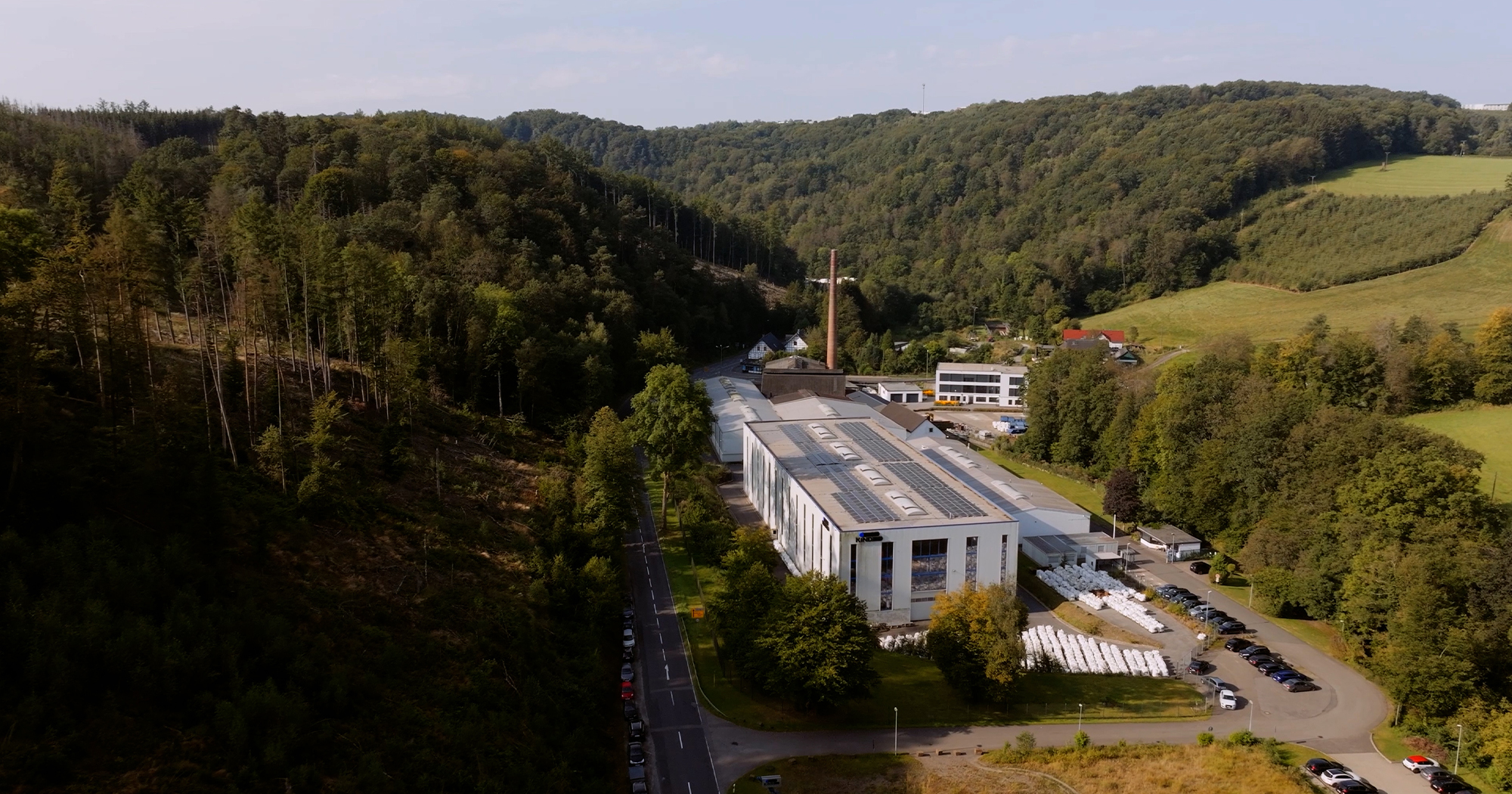 Arbeiter mit Schutzhelm betrachtet glühenden Stahlblock im Werk