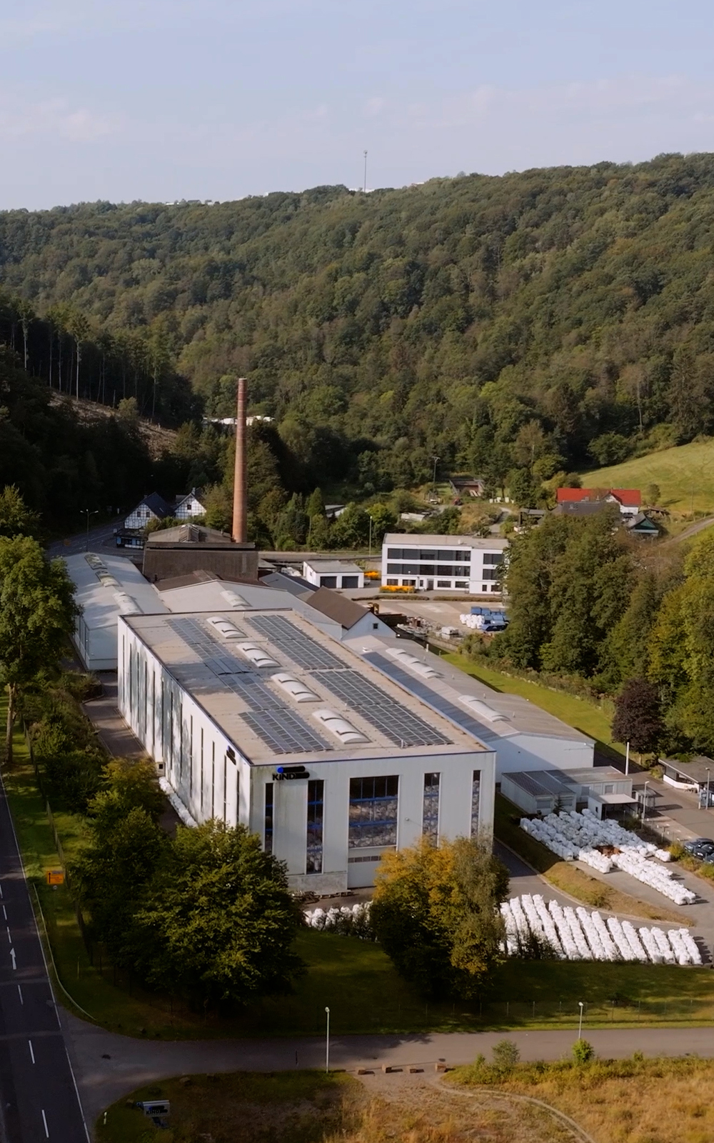Arbeiter mit Schutzhelm betrachtet glühenden Stahlblock im Werk