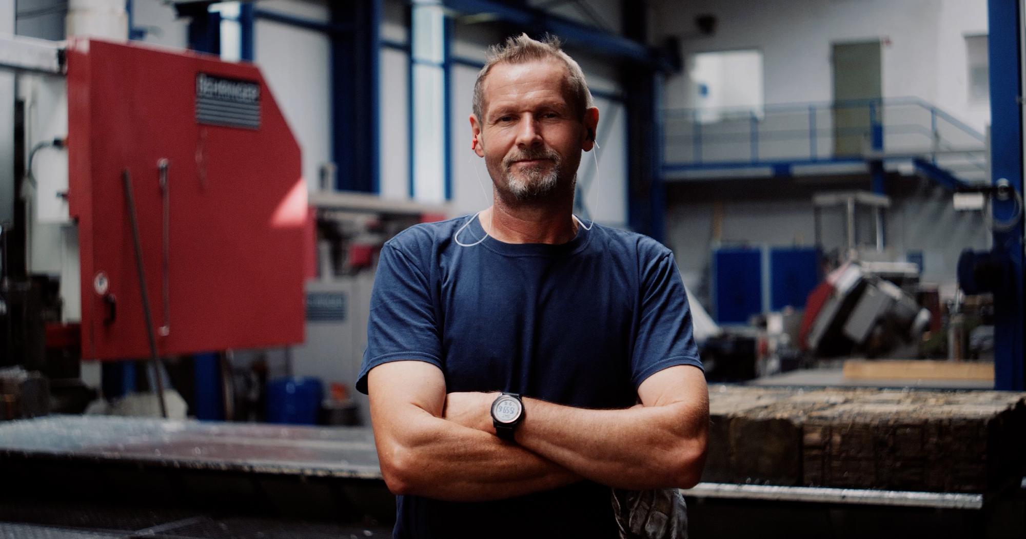 Mitarbeiter der Rolf Kind GmbH mit verschränkten Armen in der Fertigungshalle