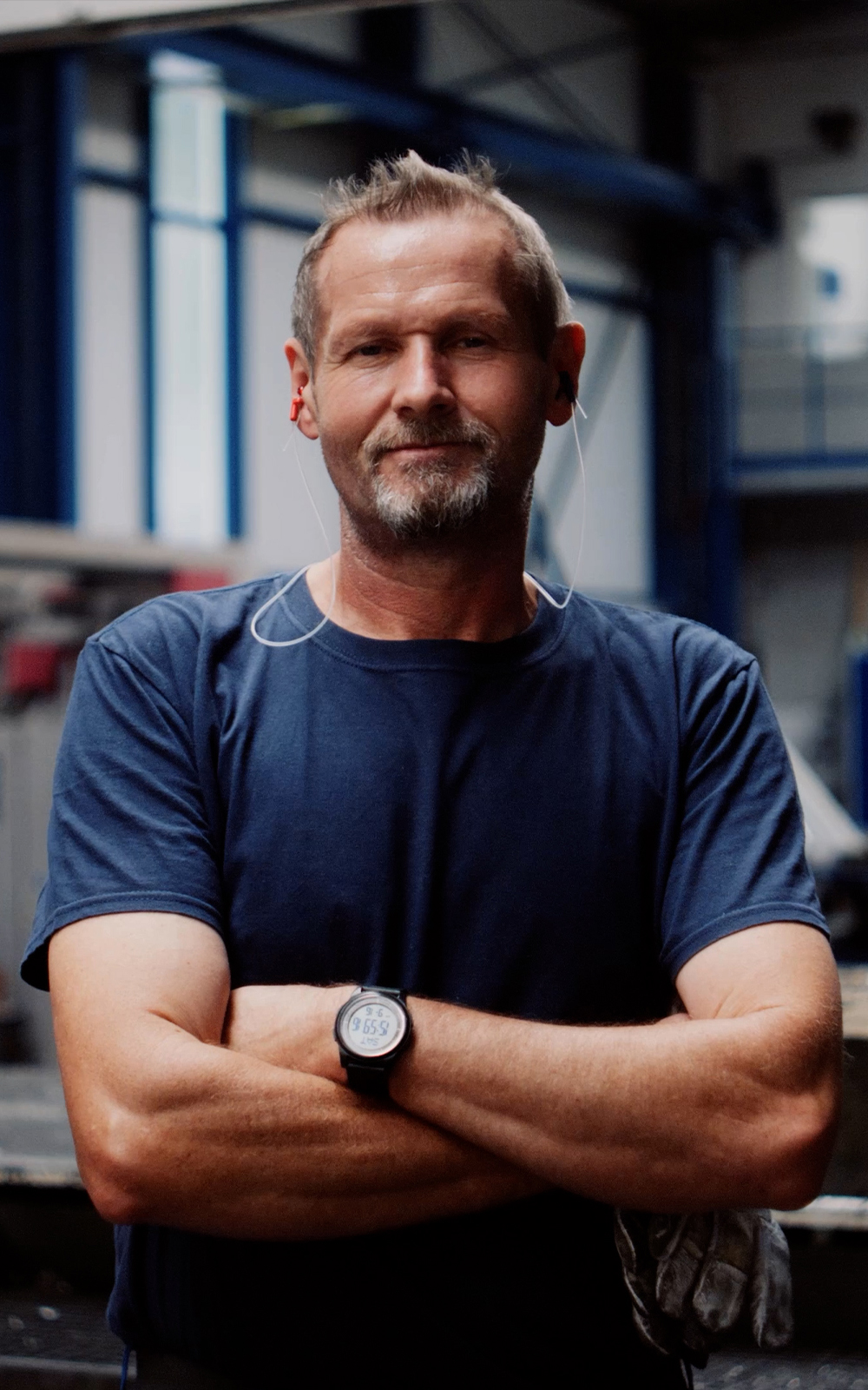 Mitarbeiter der Rolf Kind GmbH mit verschränkten Armen in der Fertigungshalle