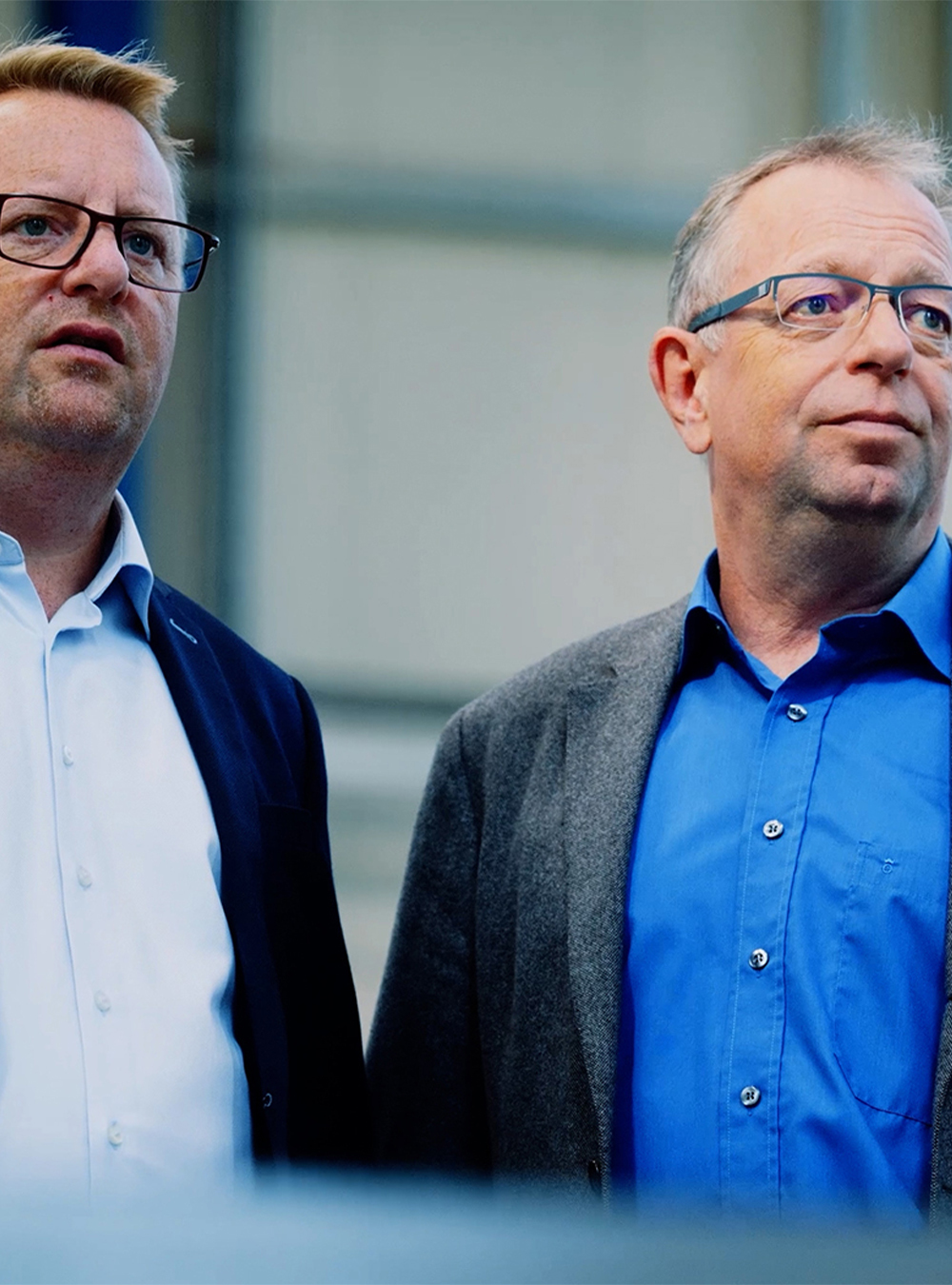 Zwei Geschäftsführer der Rolf Kind GmbH im Gespräch vor industrieller Kulisse