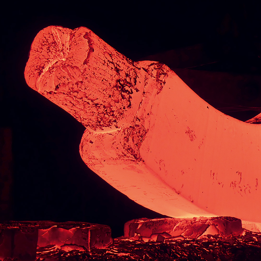 Man sieht ein Stück glühendes, gebogenes Metall.