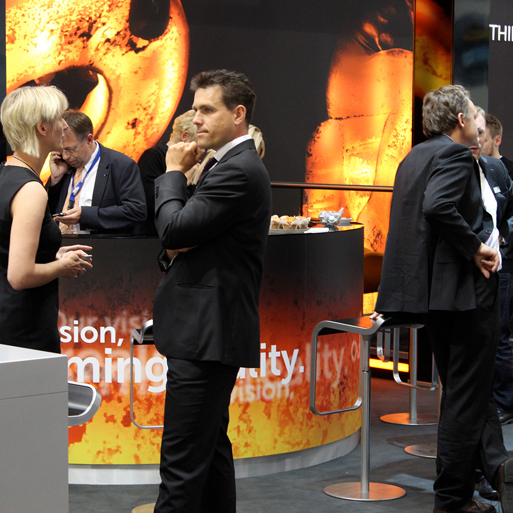 Das Foto zeigt Menschen auf dem Messestand von RKind, die sich unterhalten.