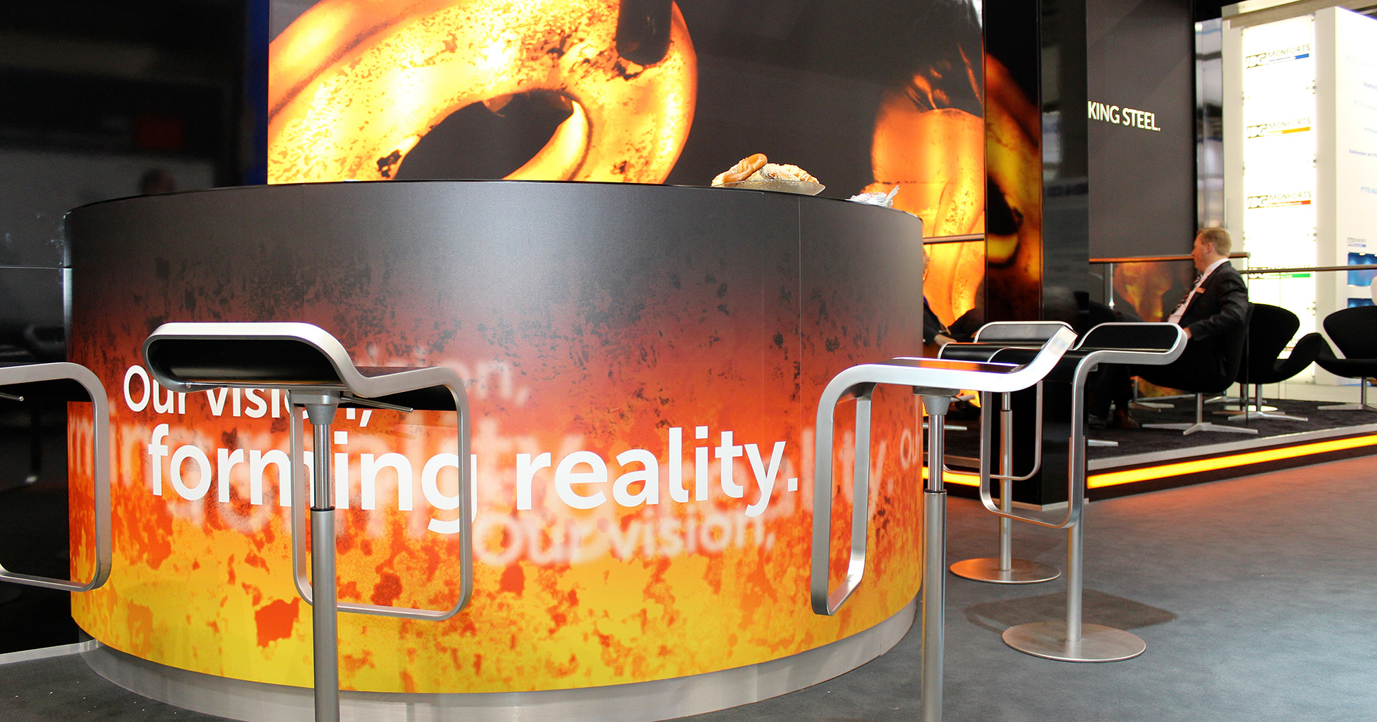 Das Foto zeigt einen runden Hochtisch mit Barhockern und RKind-Branding auf einer Messe.