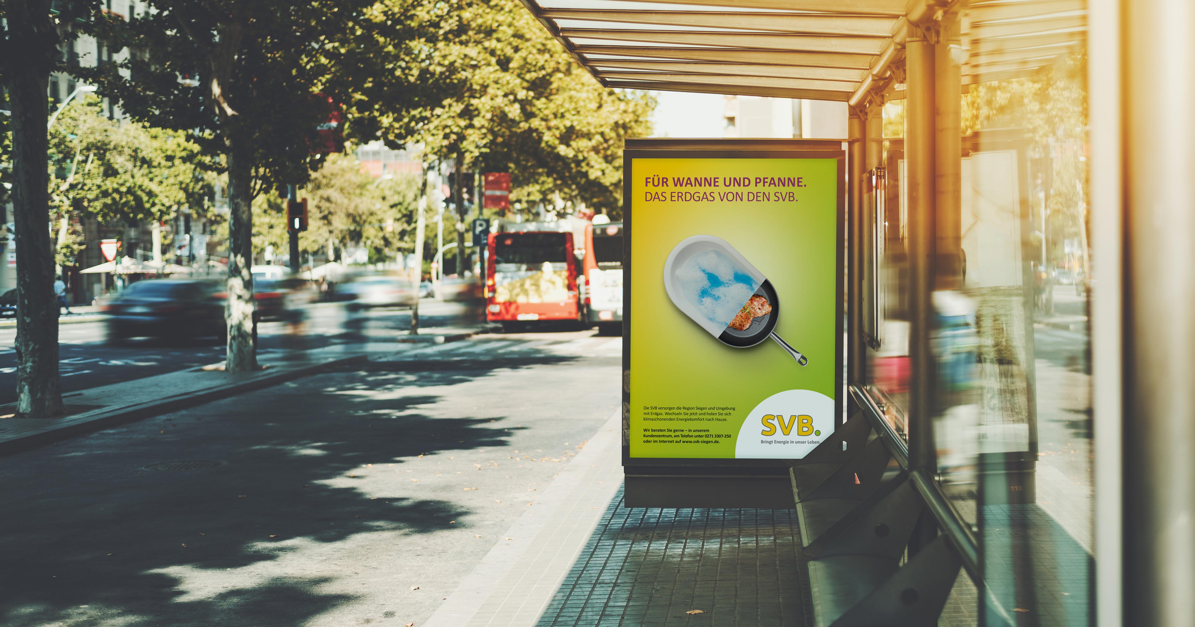 Das Foto zeigt ein Citylight an einer Bushaltestelle. Man sieht ein Poster, auf dem ein Motiv, das halb Badewanne und halb Bratpfanne zeigt, abgebildet ist. Darüber die Headline „Für Wanne und Pfanne. Das Erdgas von den SVB.“ auf gelb/grünem Grund.