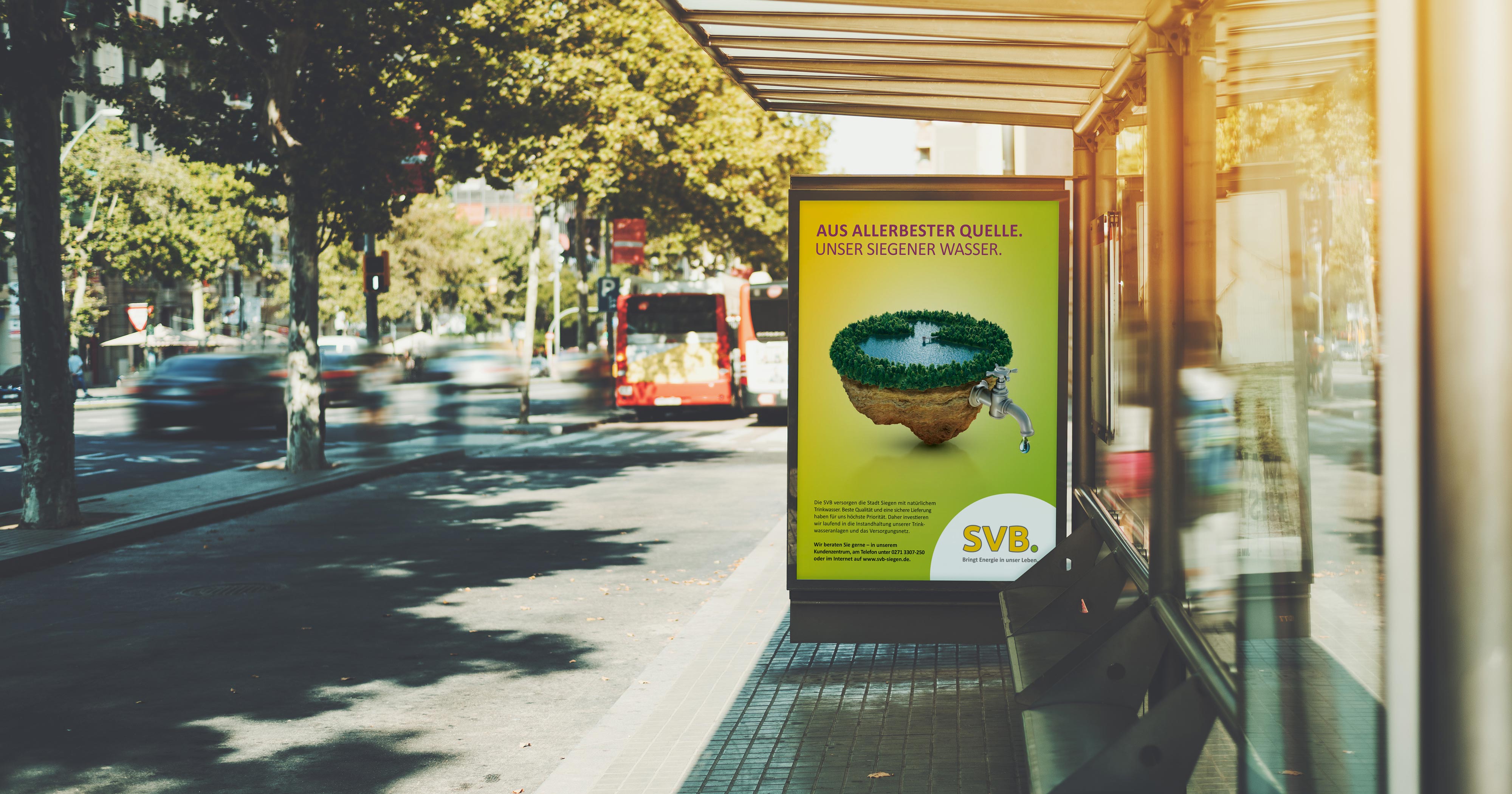 Das Foto zeigt ein Citylight an einer Bushaltestelle. Man sieht ein Poster, auf dem ein Bild eines Sees aus dem ein Wasserhahn kommt, abgebildet ist. Darüber die Headline „Aus allerbester Quelle. Unser Siegener Wasser.“ auf gelb/grünem Grund.